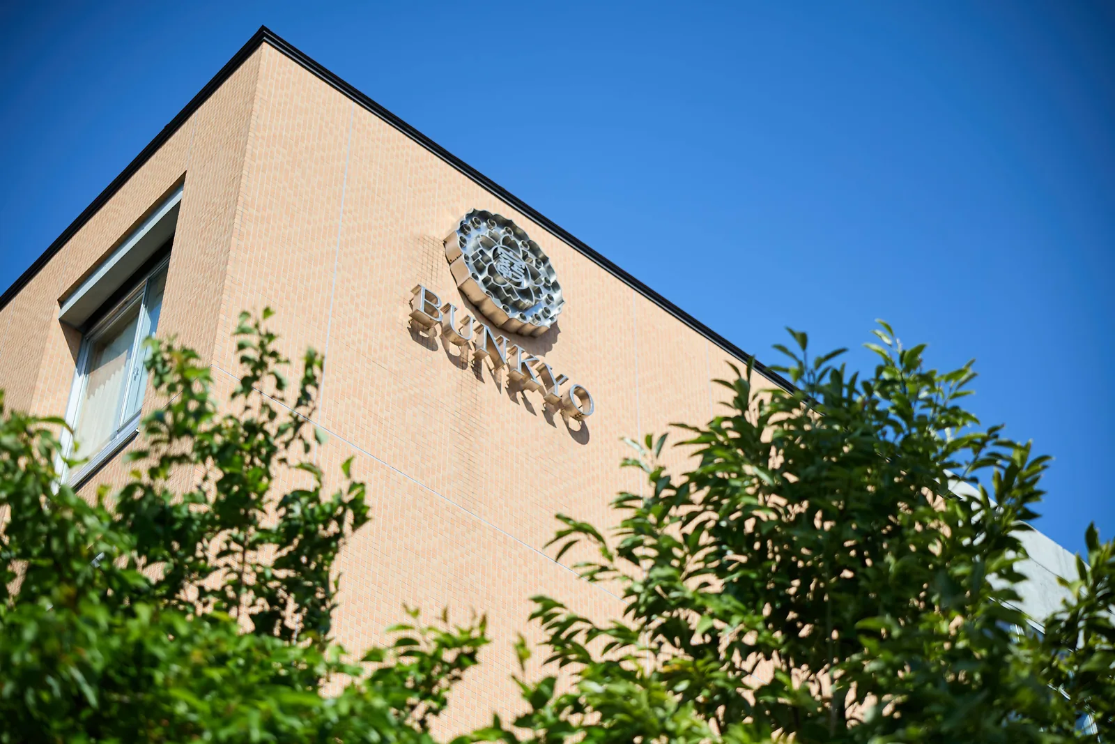 文教大学付属中学校・高等学校の校舎。れんが色の外壁に校章と「BUNKYO」の文字が掲げられている