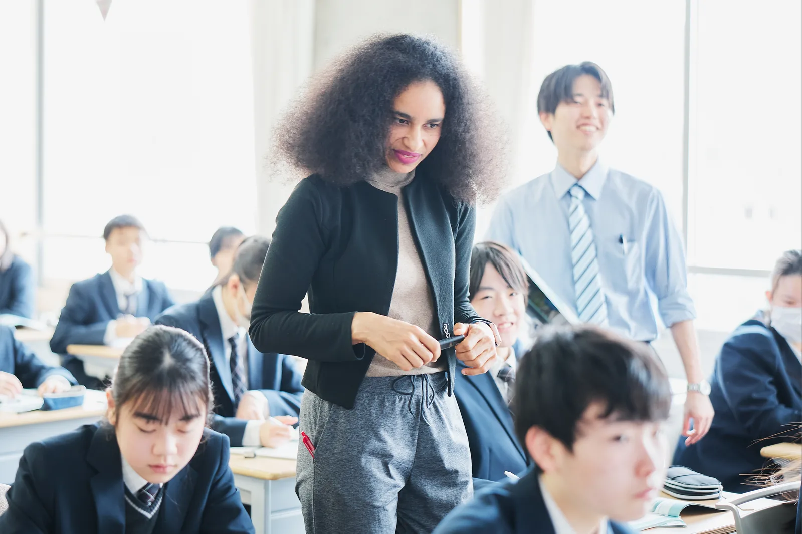 文教大学付属中学校・高等学校のGCPの授業。ネイティブ教員が机の間を回り、生徒に声をかけている