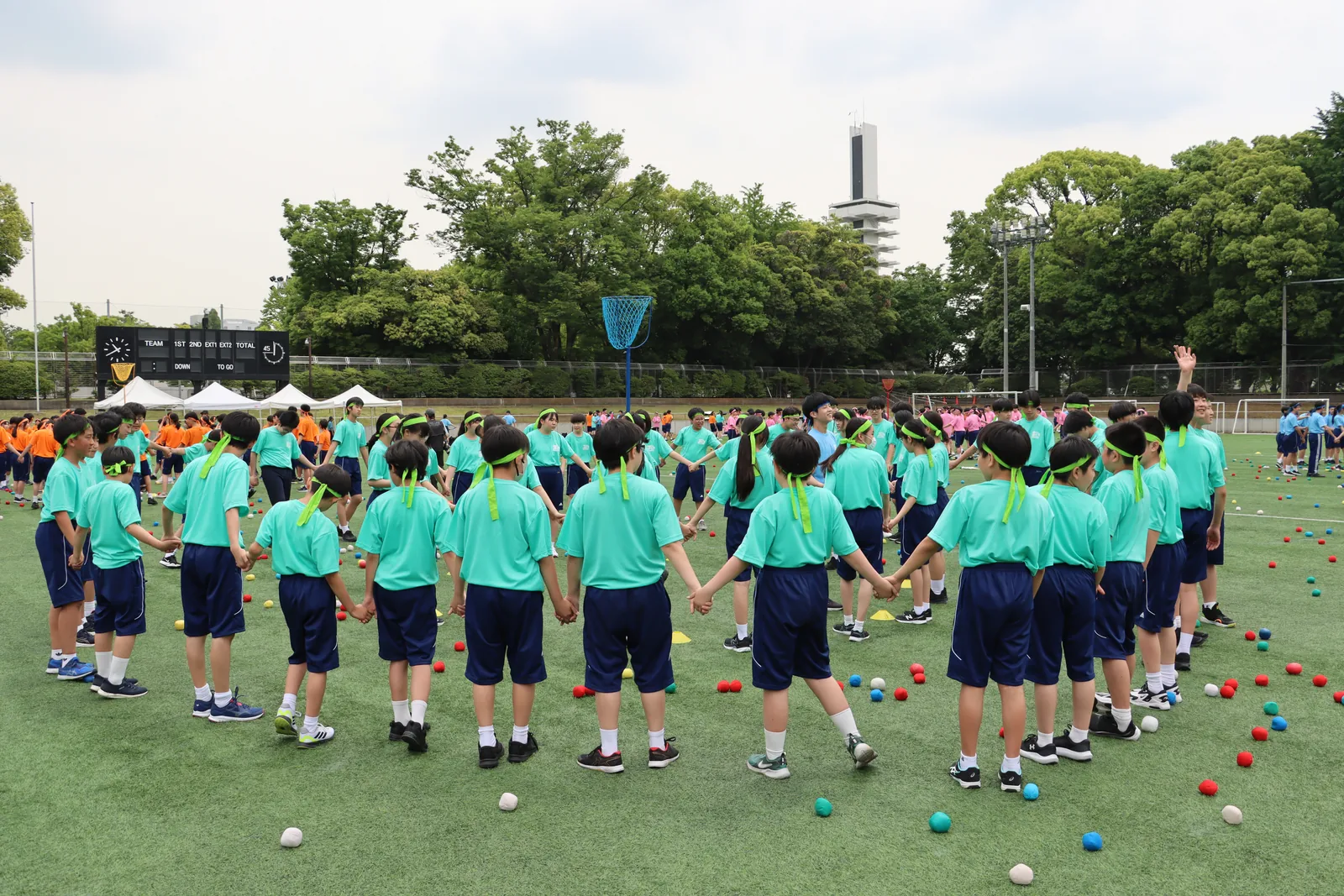 文教大学付属中学校・高等学校の体育祭。おそろいのTシャツを着た生徒たちが手をつないで大きな輪をつくっている