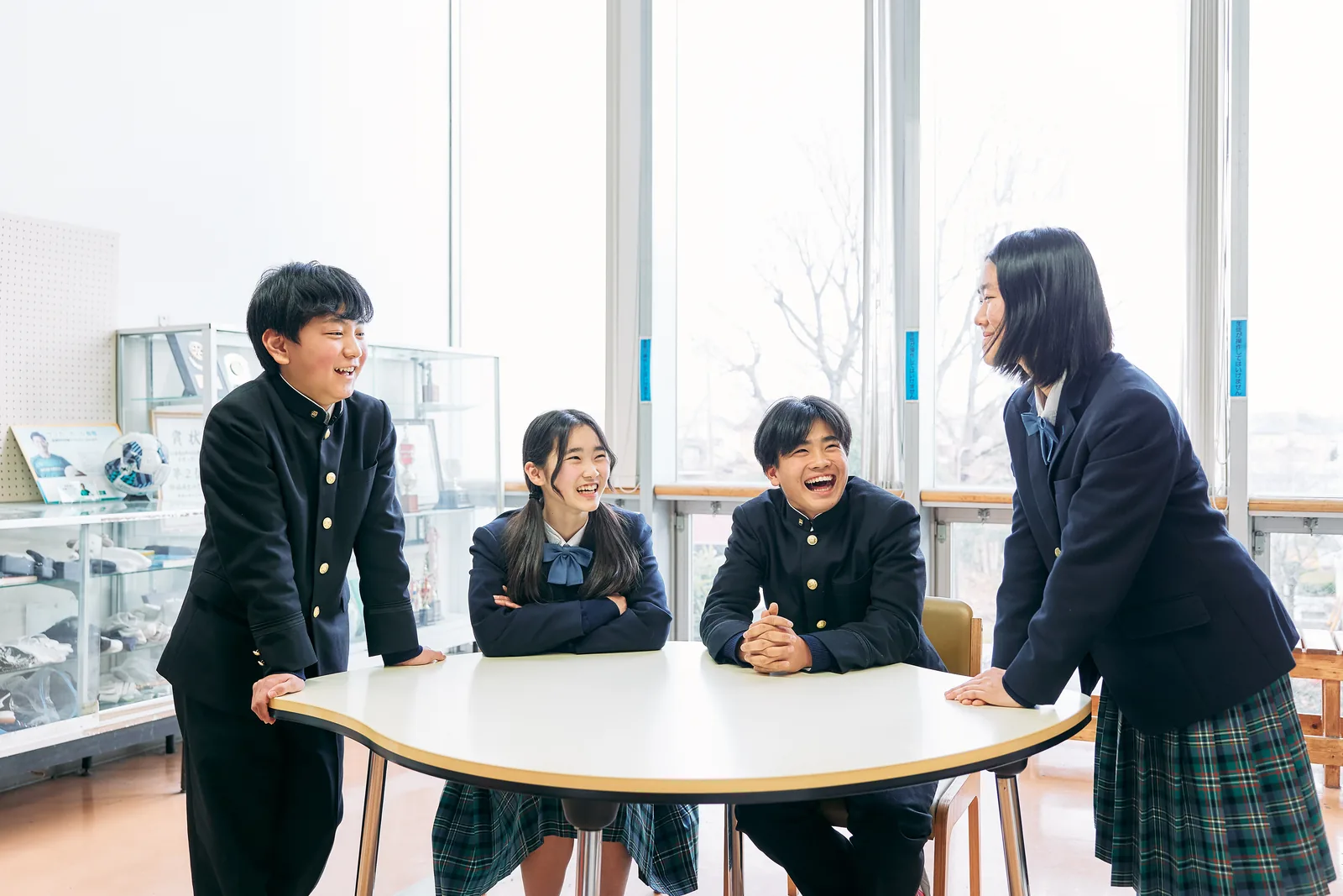獨協埼玉中学高等学校の生徒たち。窓際の丸いテーブルを囲んで4人の生徒が笑顔で話している