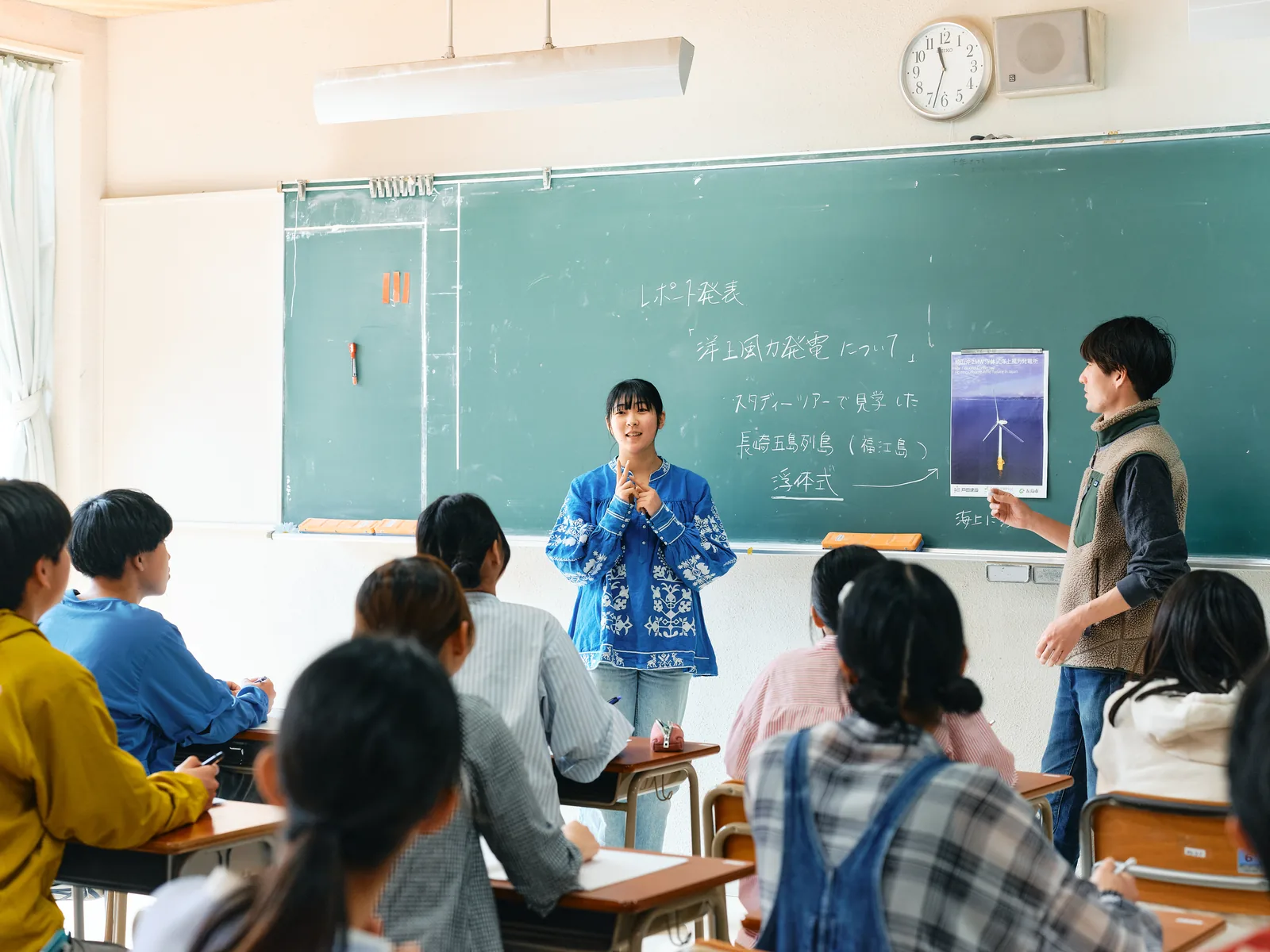 自由の森学園の教室での授業の様子。黒板の前で生徒がレポート発表をしている
