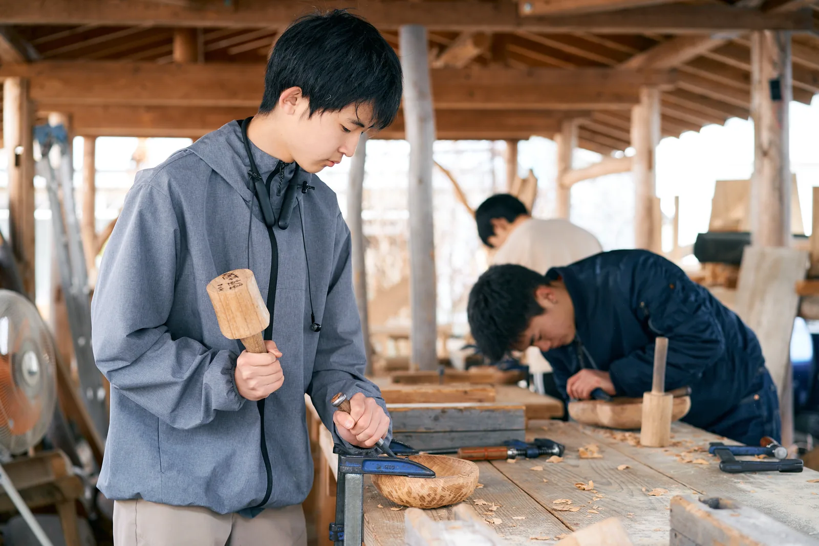 自由の森学園の工房で、木づちとのみを使って木の器を彫る生徒たち