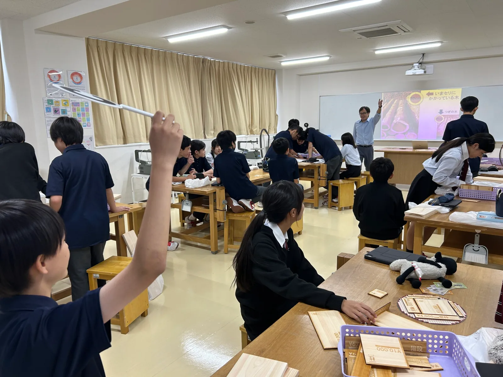 開智所沢中等教育学校の授業の様子。木製の作業台が並ぶ教室で、生徒がのこぎりを手に作業している