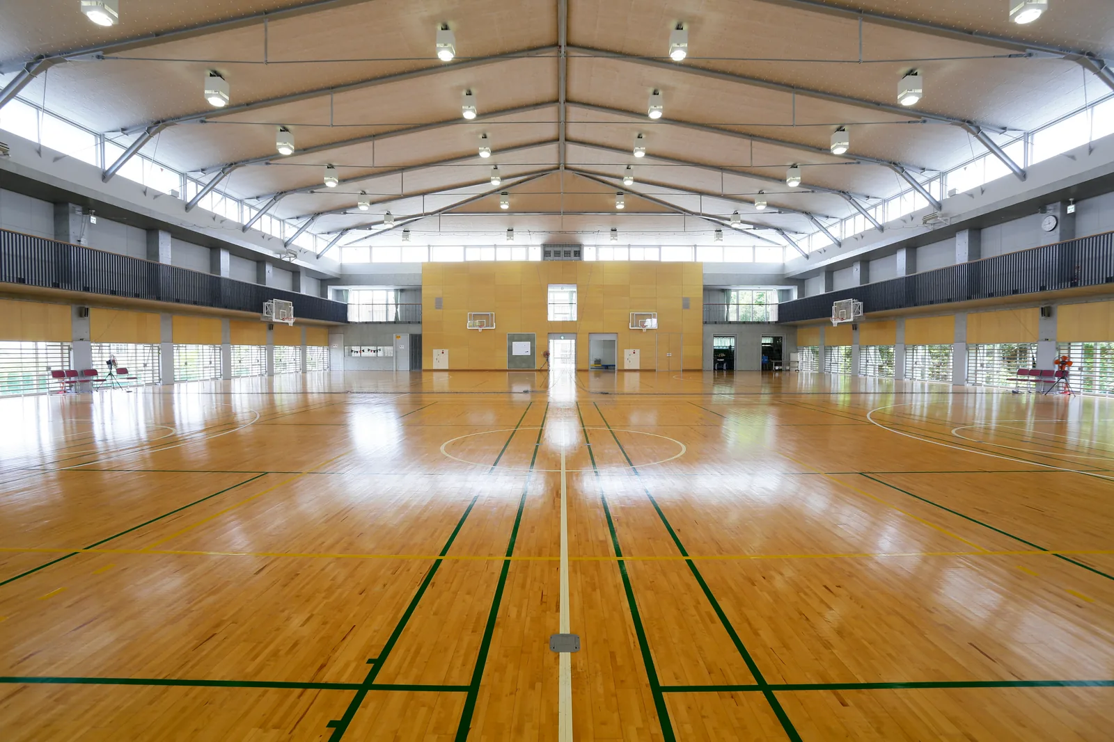聖園女学院中学校・高等学校のマリアホールのメインアリーナ。高い天井の下に木の床が広がり、バスケットボールのゴールが並んでいる