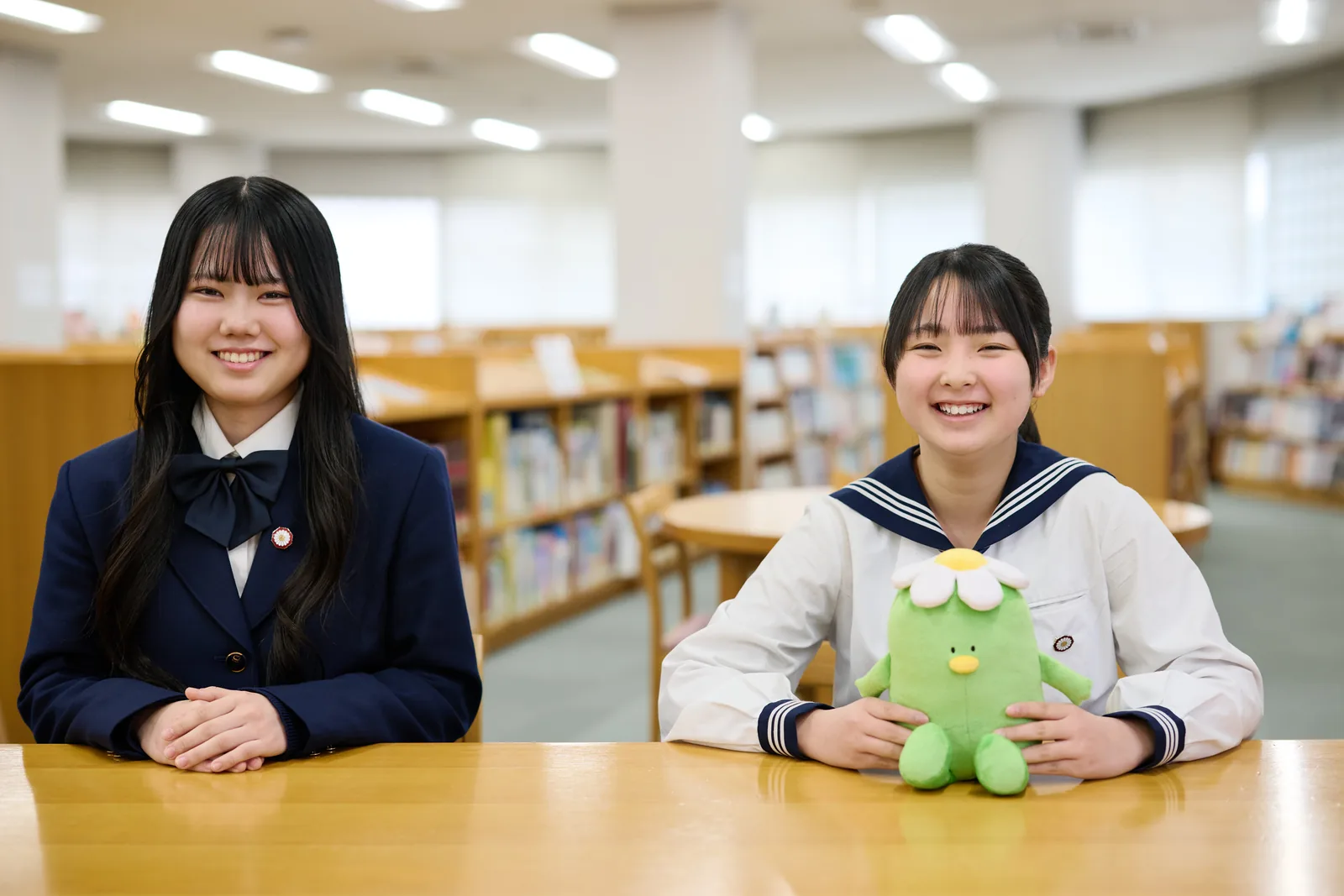 相模女子大学中学部・高等部の図書室で、生徒が机に着き、学園キャラクター「さがっぱ・ジョー」のぬいぐるみを手にしている