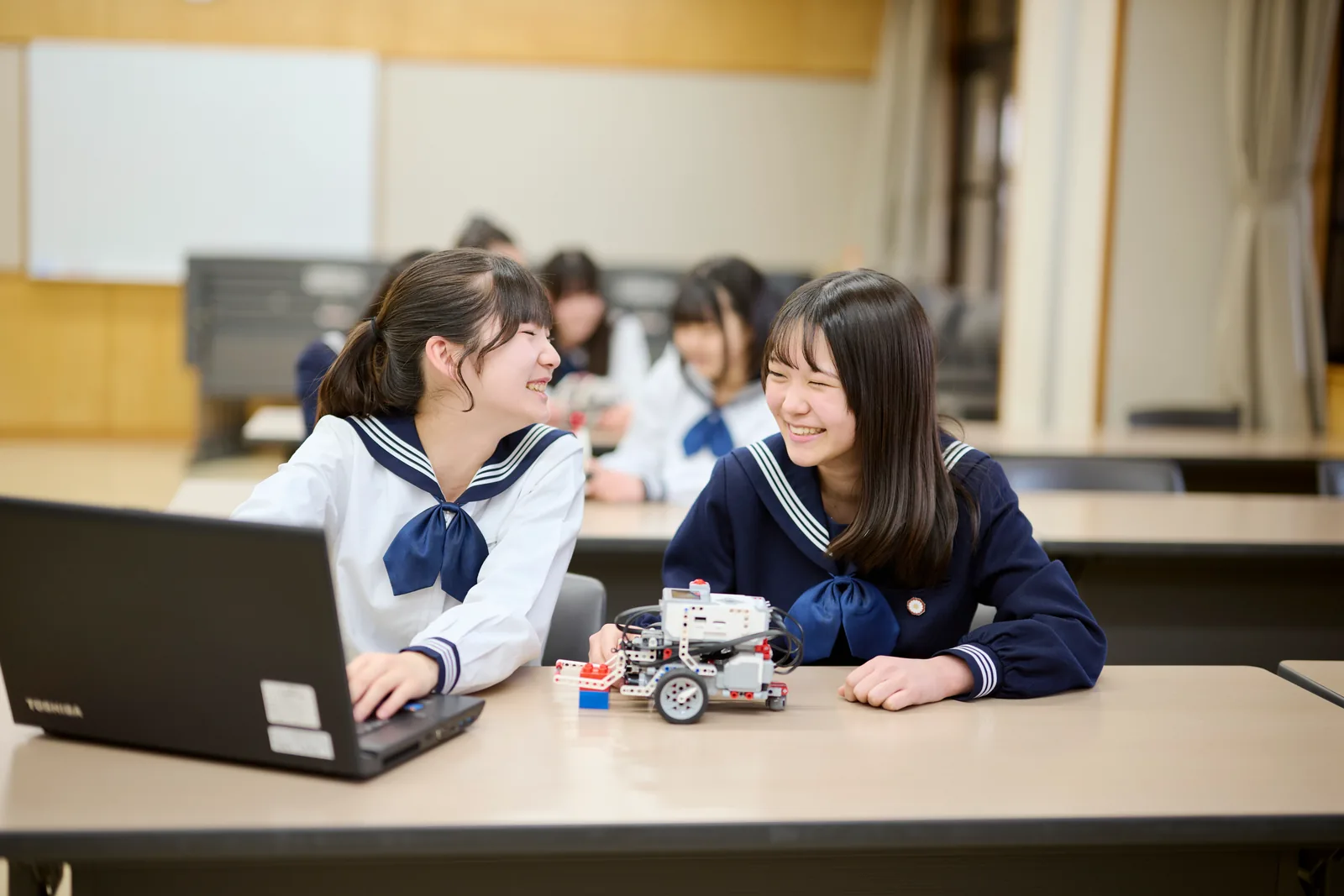 相模女子大学中学部・高等部の生徒が、ノートパソコンとロボット教材を机に置いて取り組んでいる様子