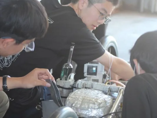 東京都市大学付属中学校・高等学校の自動車部。部員が車両のエンジンまわりを整備している