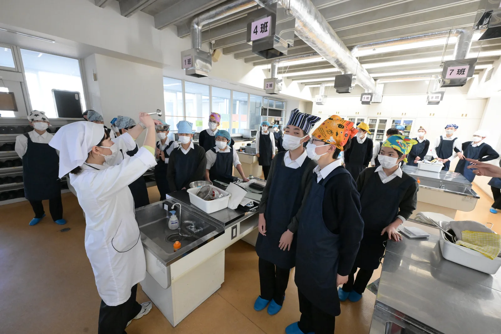 東京都市大学付属中学校・高等学校の家庭科の調理実習。エプロンを着けた生徒が調理台を囲んでいる