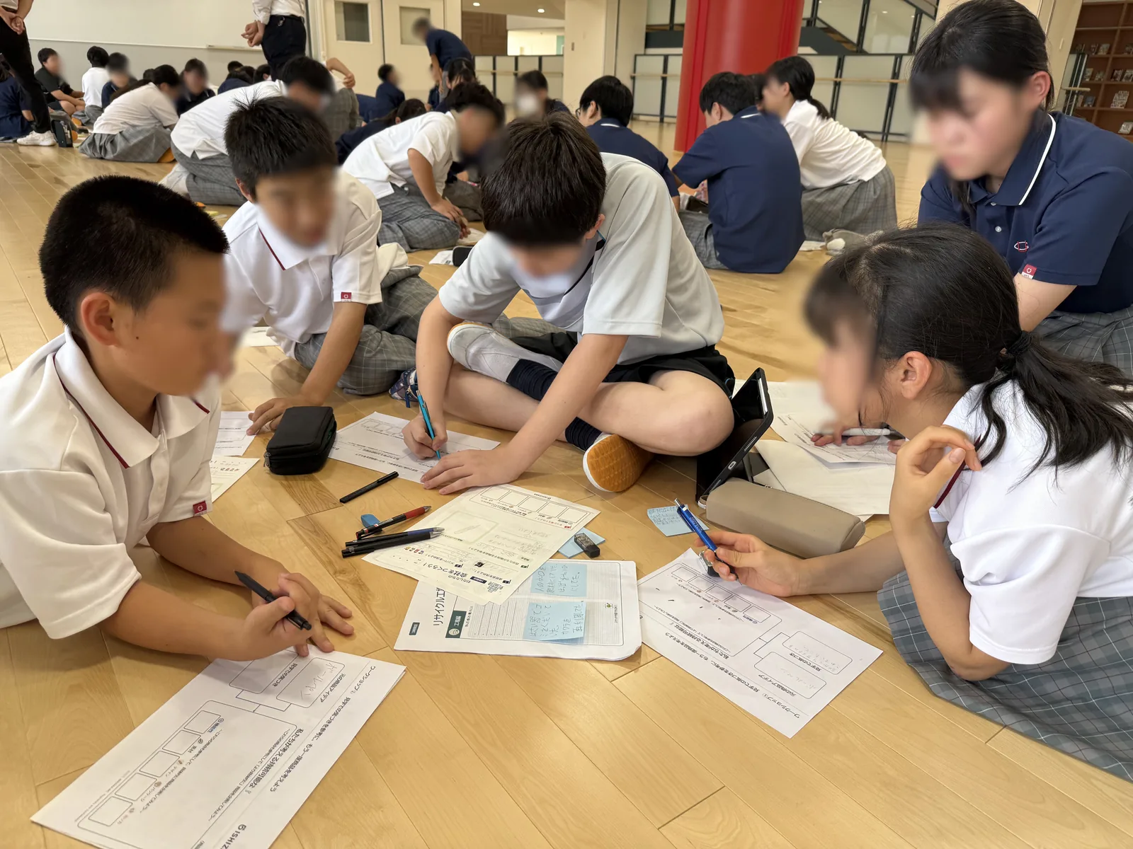 浦和学院中学校の生徒が、探究プログラム「ラーニングジャーニー」の事後学習で、床に座って筆記具を手にワークシートに書き込んでいる様子