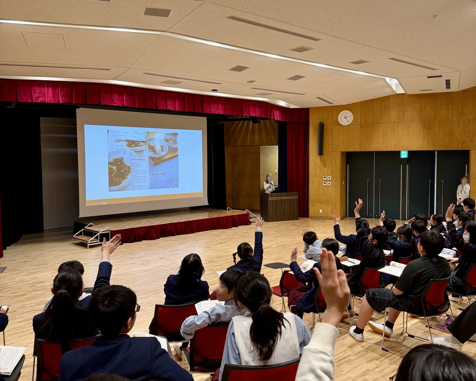 浦和学院中学校のUGCホールでの道徳の授業。スクリーンに資料が映され、生徒が一斉に手を挙げている