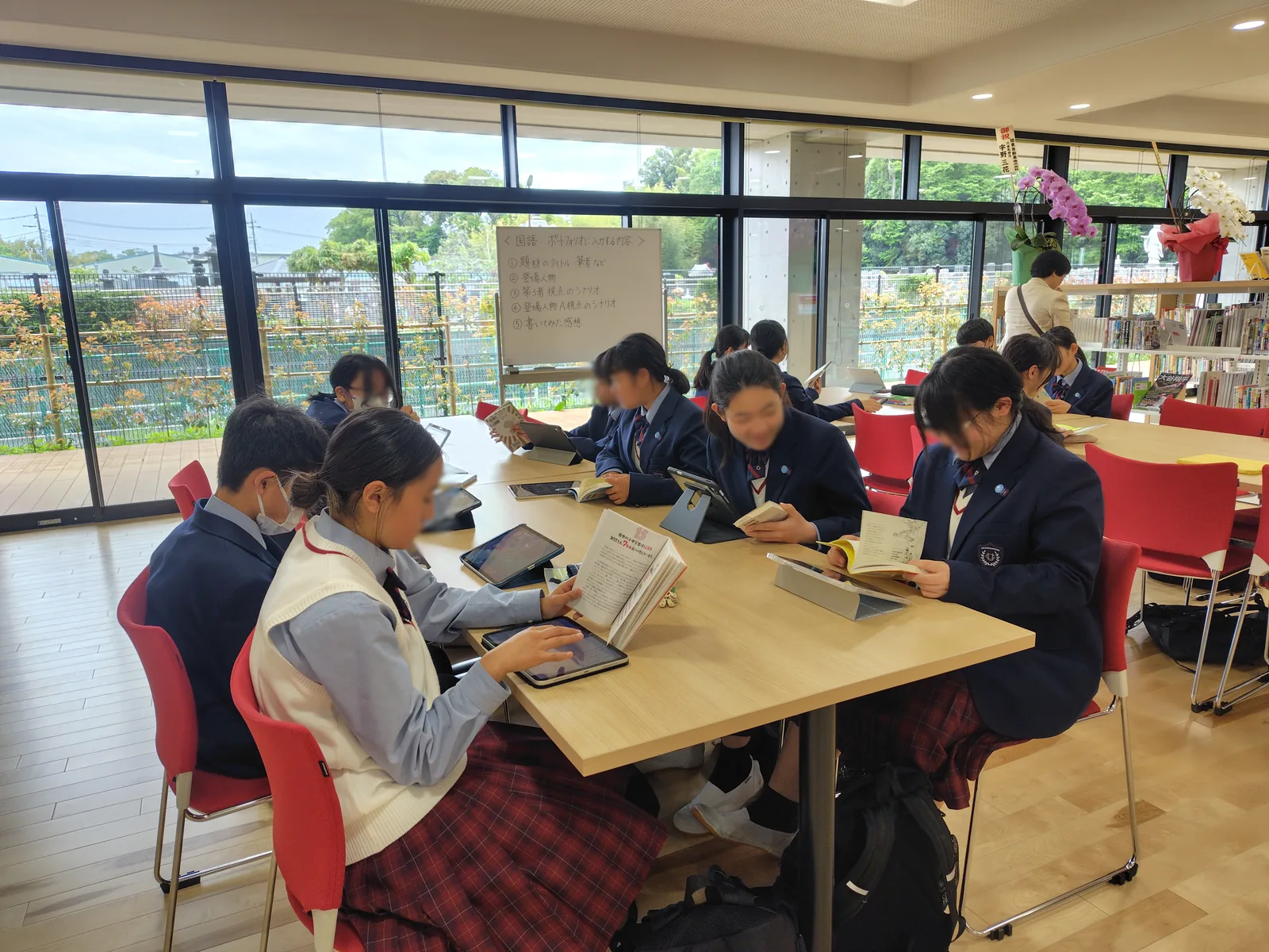 浦和学院中学校の授業の様子。窓に面した明るいスペースで、生徒が机を囲み、本とタブレットを開いている