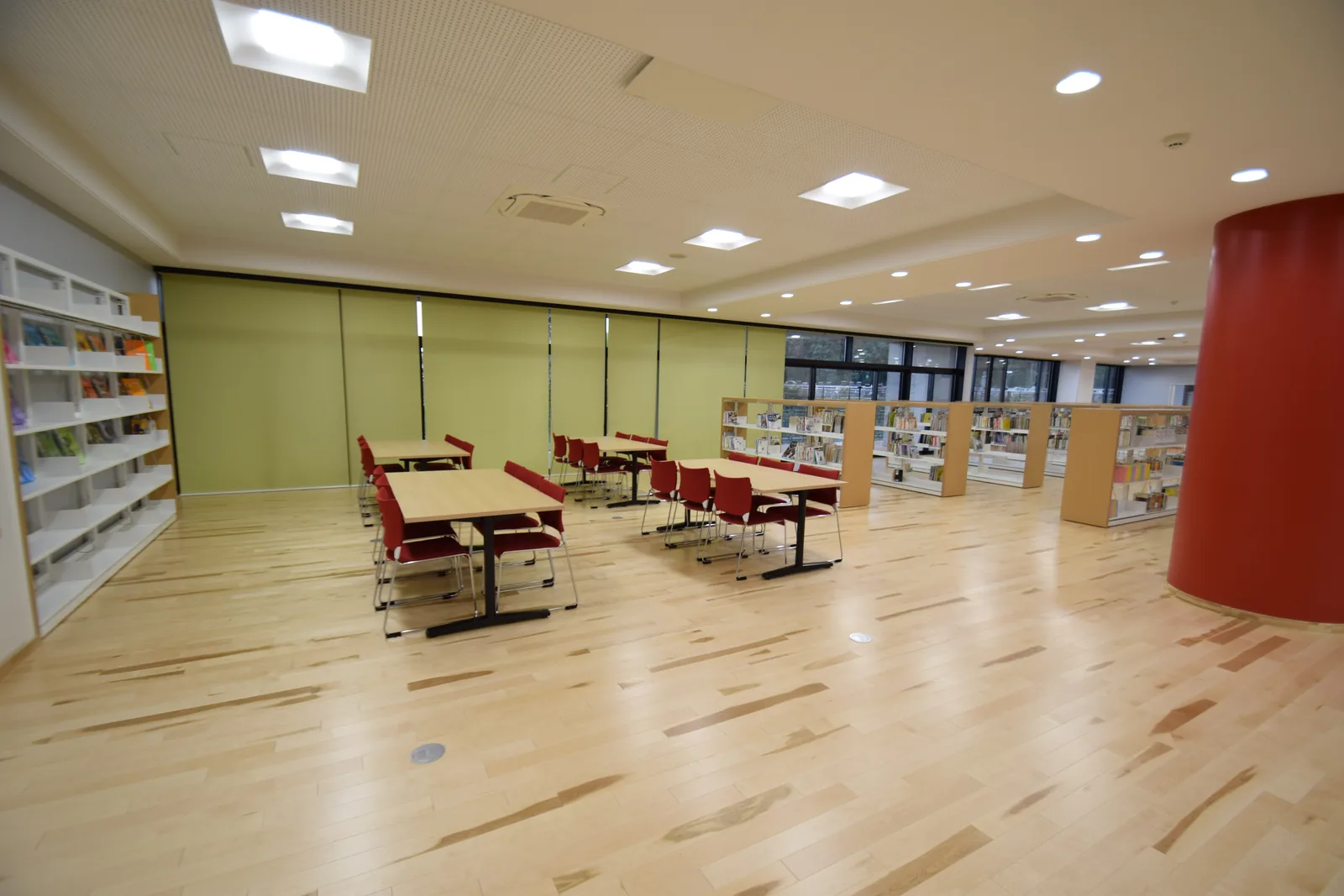 浦和学院中学校のメディアセンター。木の床に閲覧用の机と赤い椅子が並び、奥に書架が並んでいる